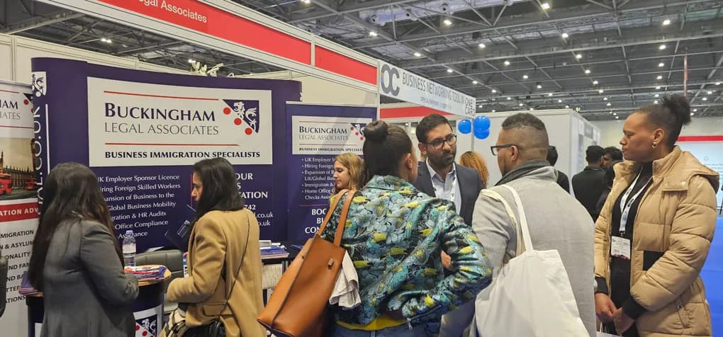 Team members speaking with attendees at a business immigration event